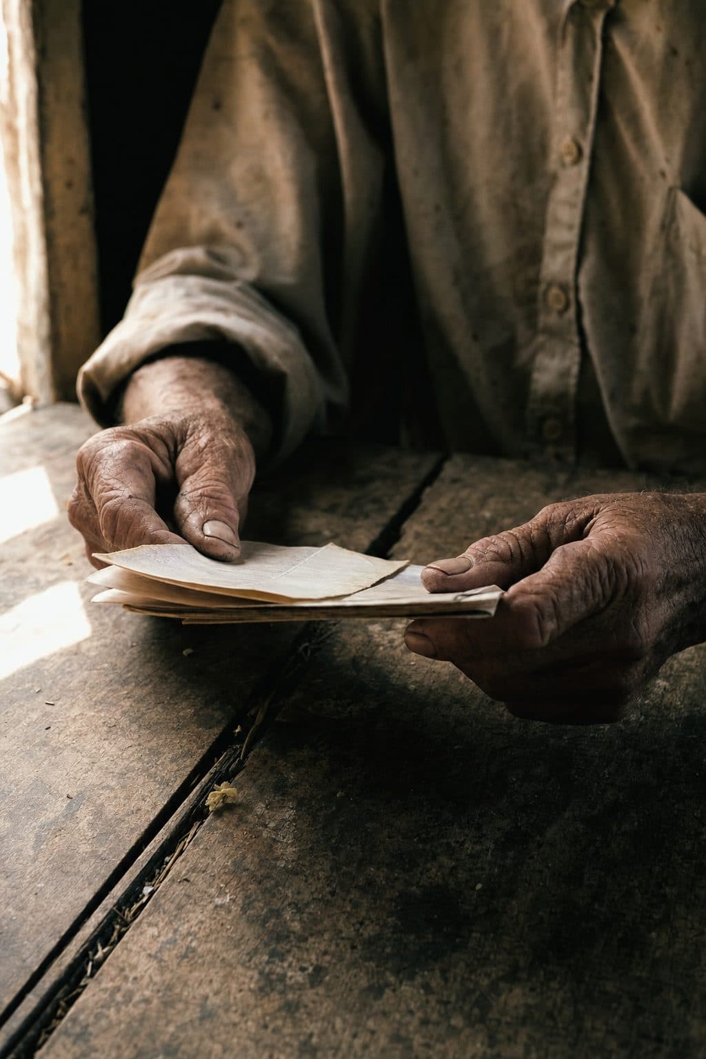 Mãos de trabalhador rural sobre documentos numa mesa de madeira